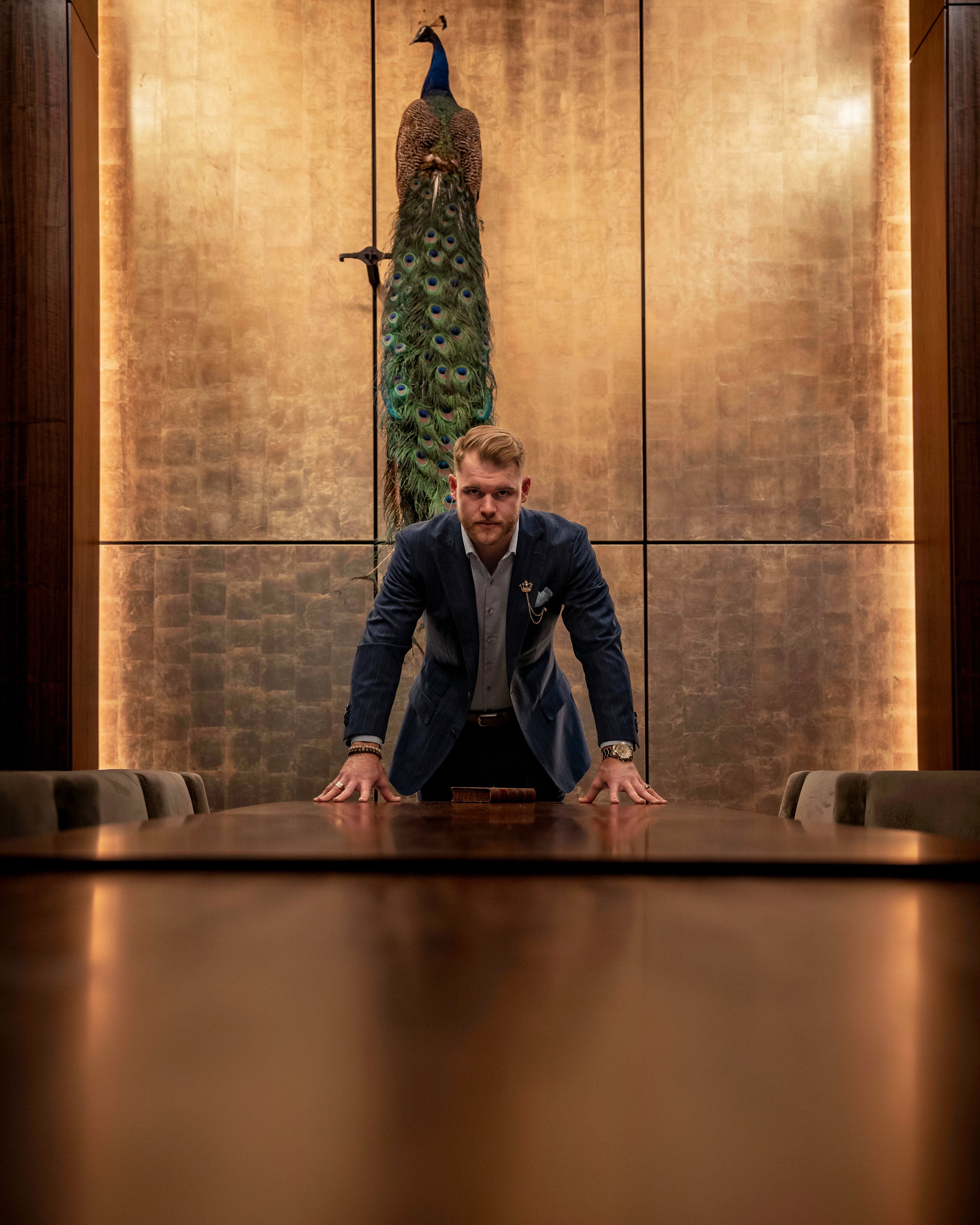 Navy pinstripe suit laid across a boardroom table against a gold-leaf wall