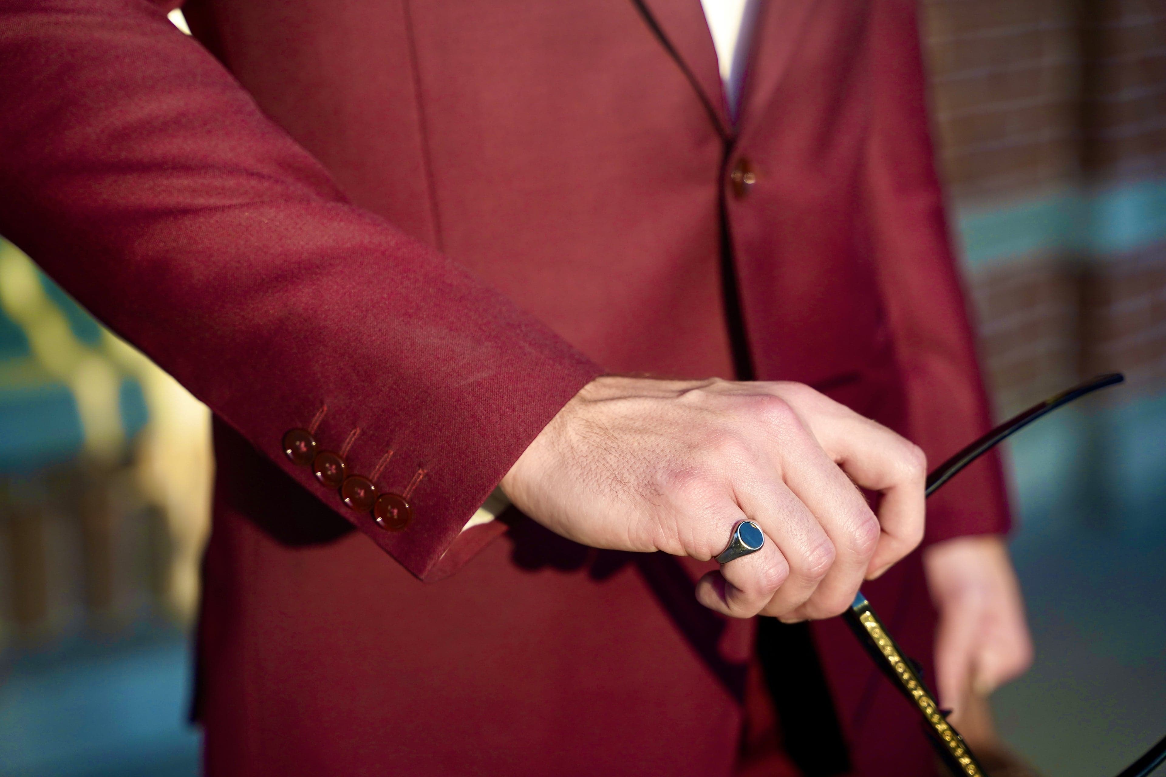 Burgundy sleeve with signet ring and sunglasses